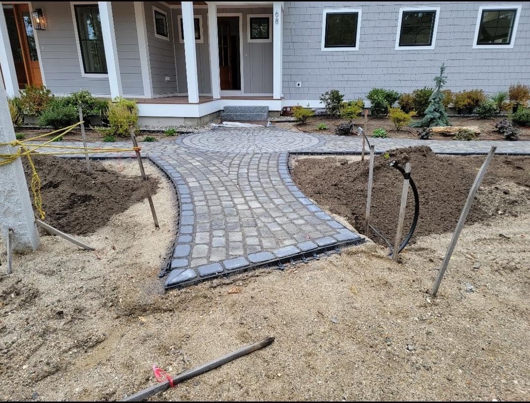 Clean cobblestone entry walkway in front of a shingled Maine home