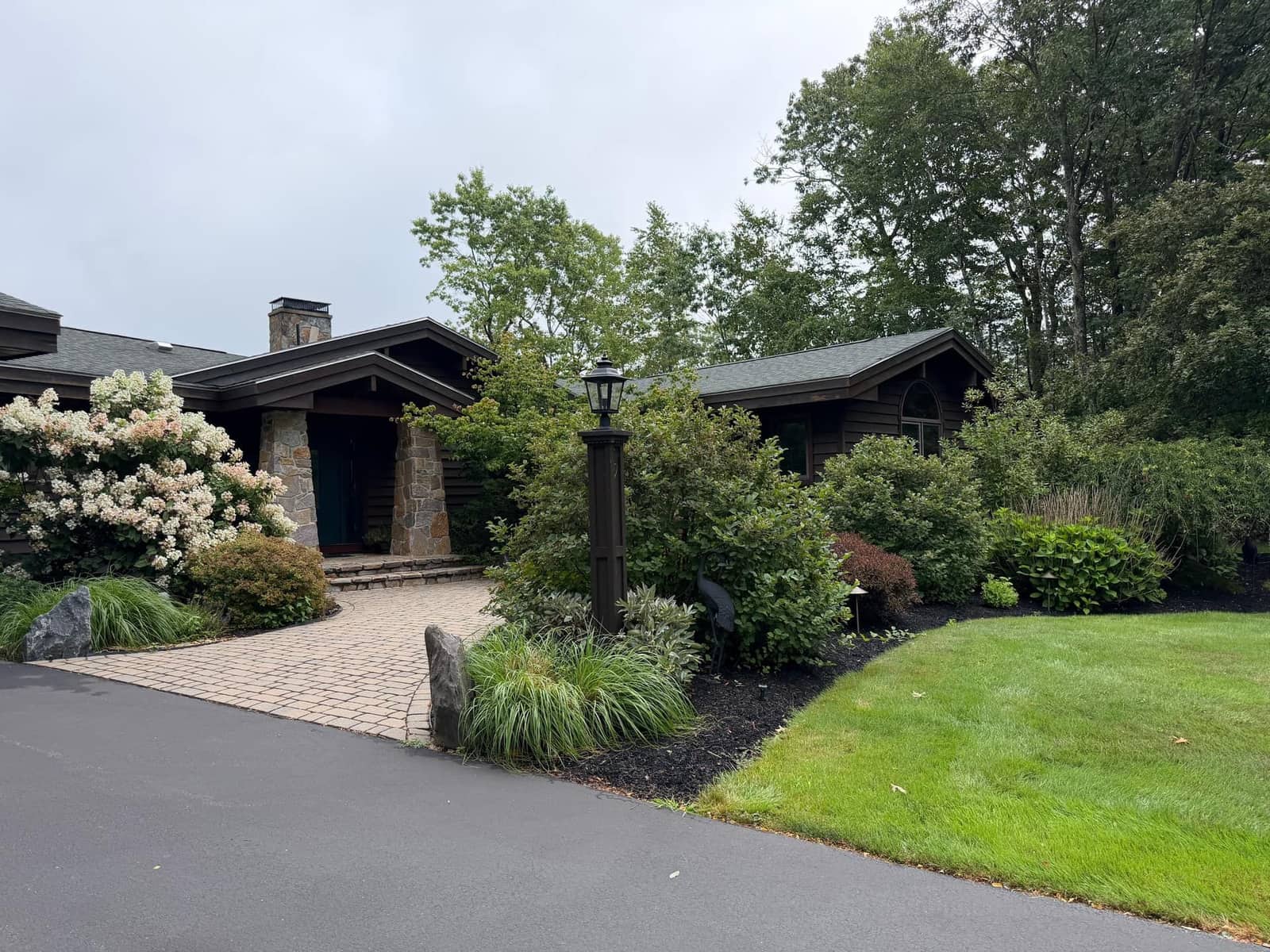 Craftsman home entry with paver walkway framed by layered foundation plantings